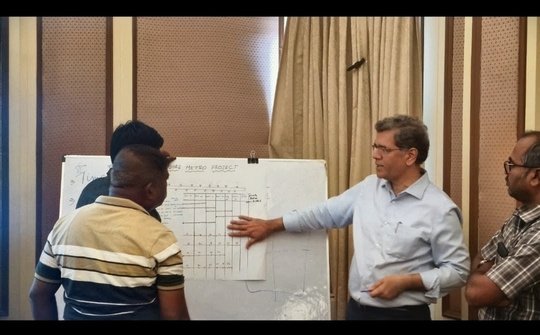 Pradeep Sangal discussing a project plan with participants at a whiteboard